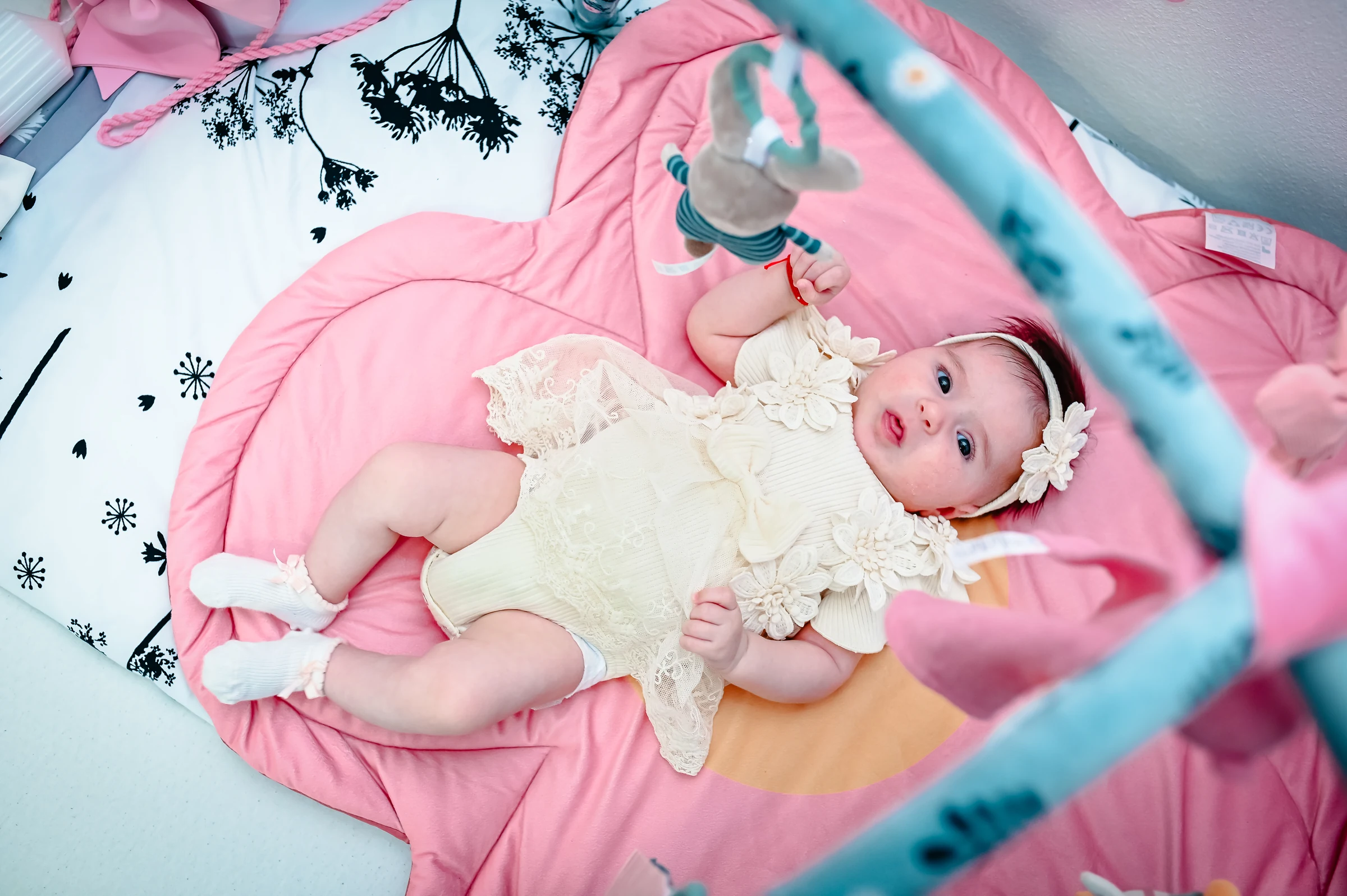 Baby in einem hellen Outfit auf einer Spieldecke