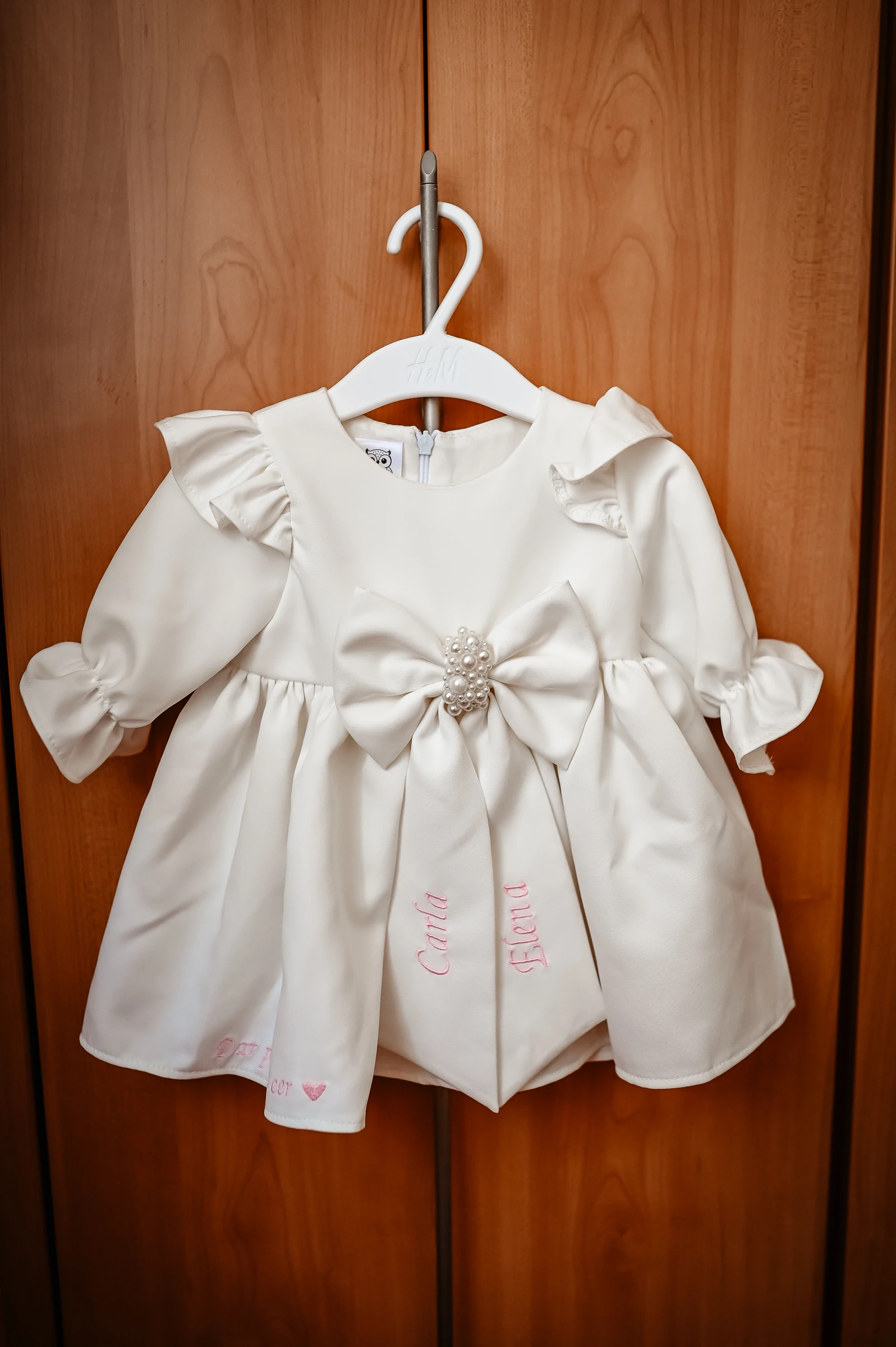 Weißes Taufkleid an einer Holztür